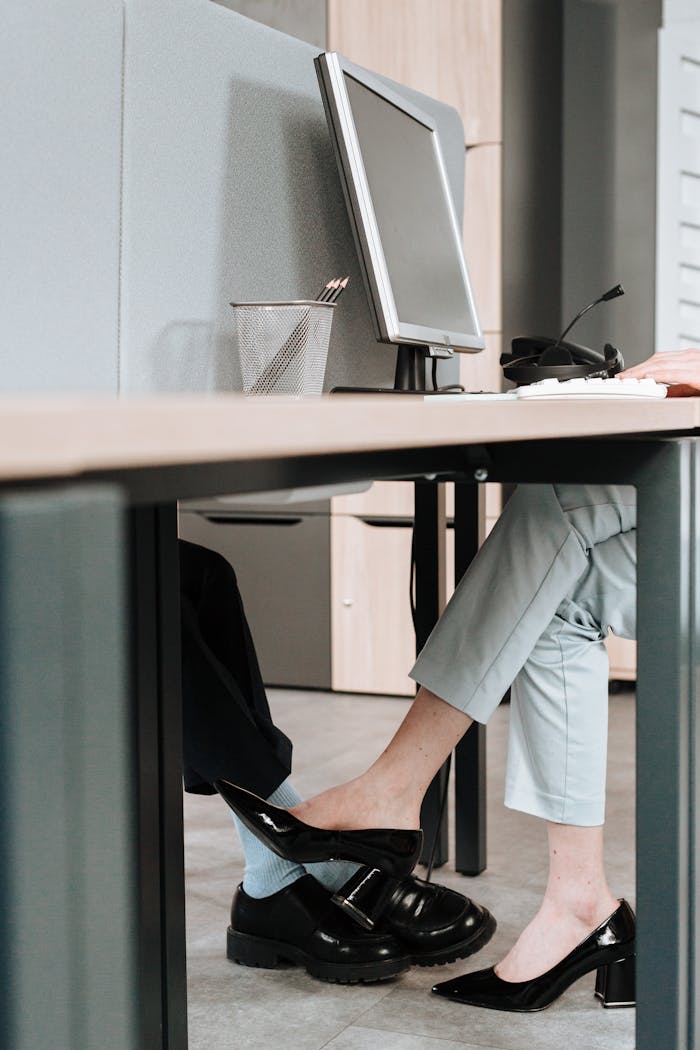 A playful moment between colleagues with foot contact under the office desk.